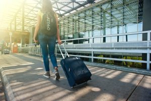 woman-walking-on-pathway-while-strolling-luggage